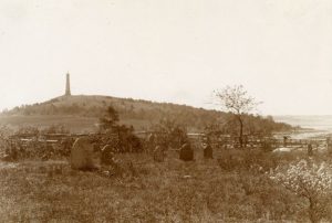 Graveyard in foreground; monument in background, on a hill. 